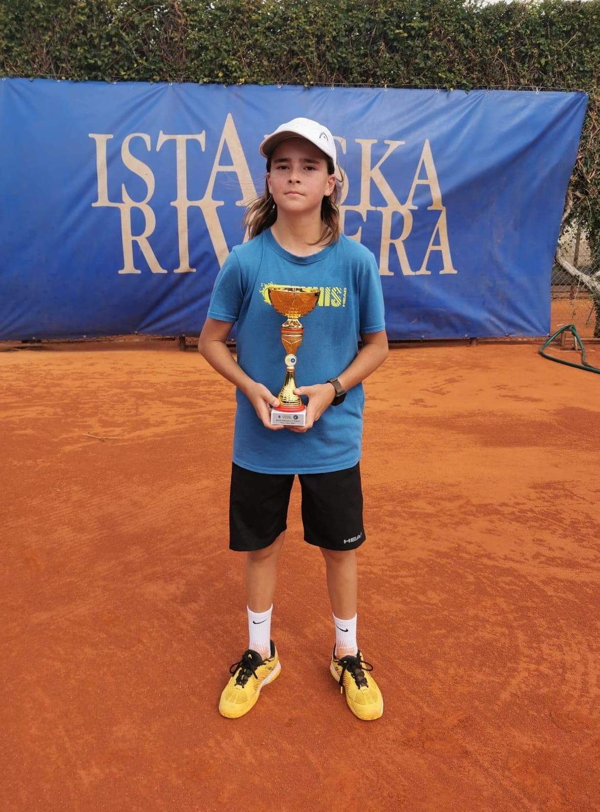 Lenart Kadriu, coupe en main, devant la bâche du tournoi Istarska Riviera