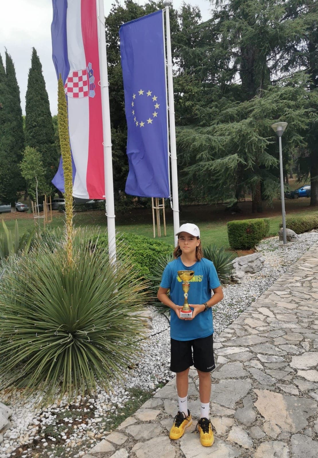 Lenart Kadriu et sa coupe devant les drapeaux de la Croatie et de l’Union européenne, tournoi Tennis Europe