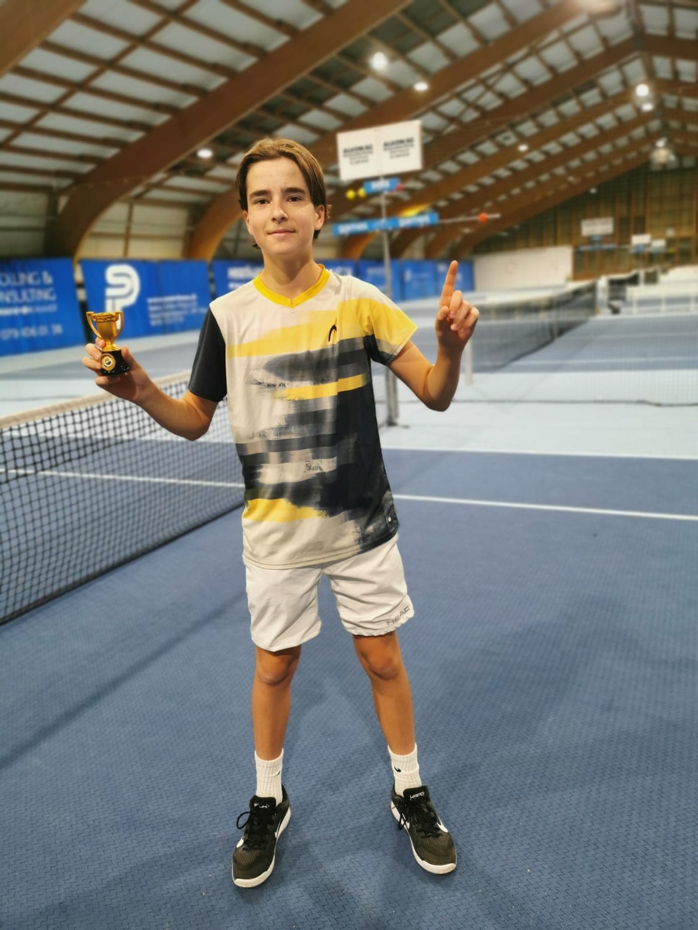 Lenart Kadriu index levé, coupe en main, après une victoire en salle